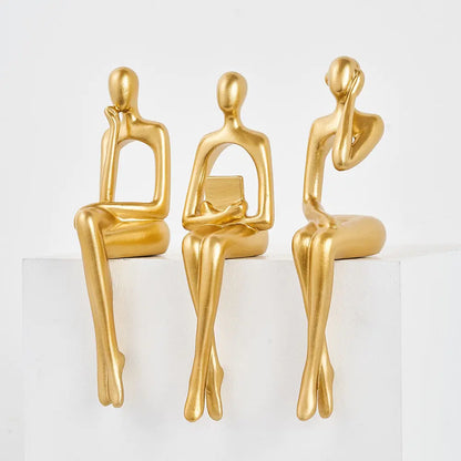 Three Nordic style decorative art figurines. Gold colored, sitting next to each other, legs down- Epiceasyshop1