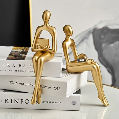 Nordic style decorative art figurines -sitting-gold colored-two pieces-one holding book, one holding transparent globe in the knee-Epiceasyshop1